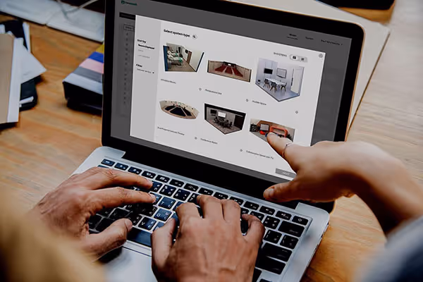 People pointing at a computer screen showing conference room design options