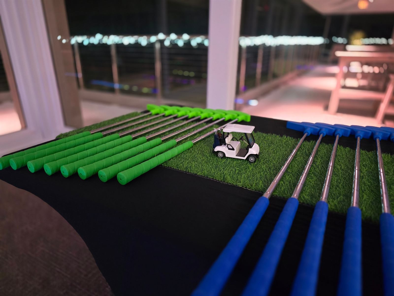 Putters laid out on a turf runner at an indoor evening event