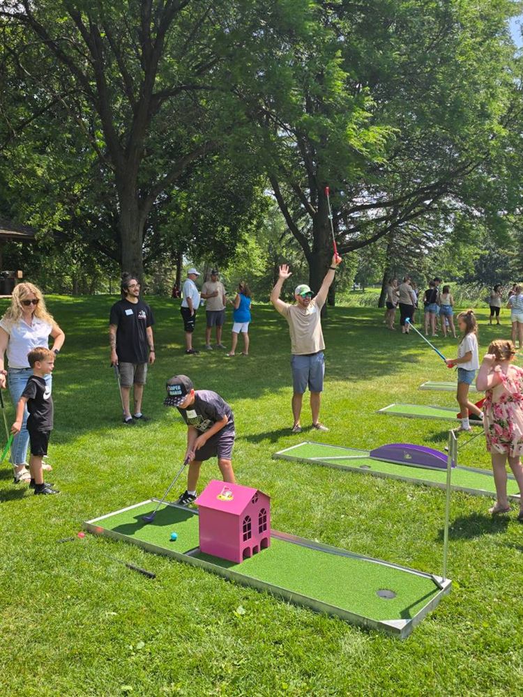 Adults and families playing portable mini golf in a Minnesota park