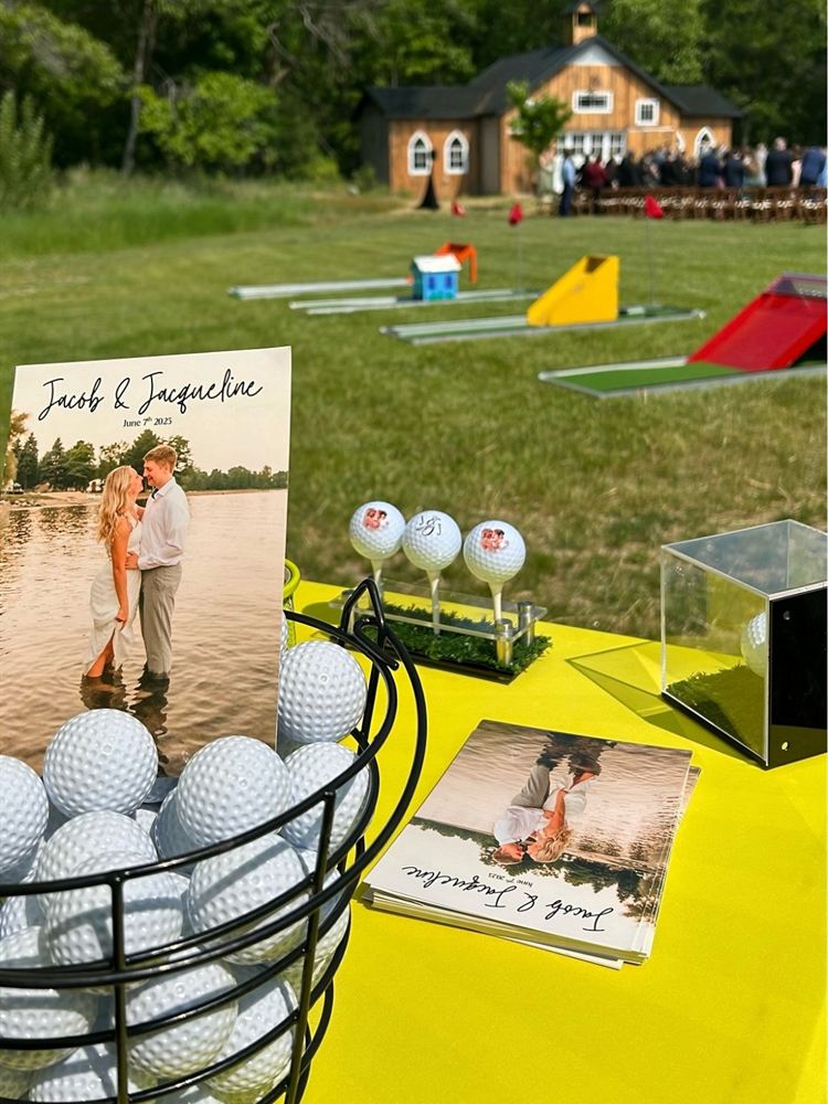 Wedding welcome table with custom golf balls and a mini golf course set up near the ceremony