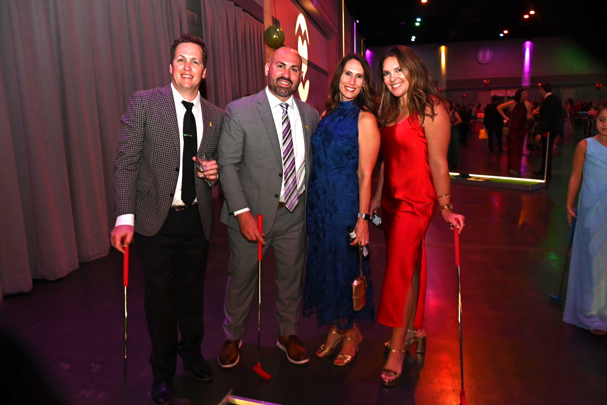 Wedding reception guests posing with putters at an evening reception