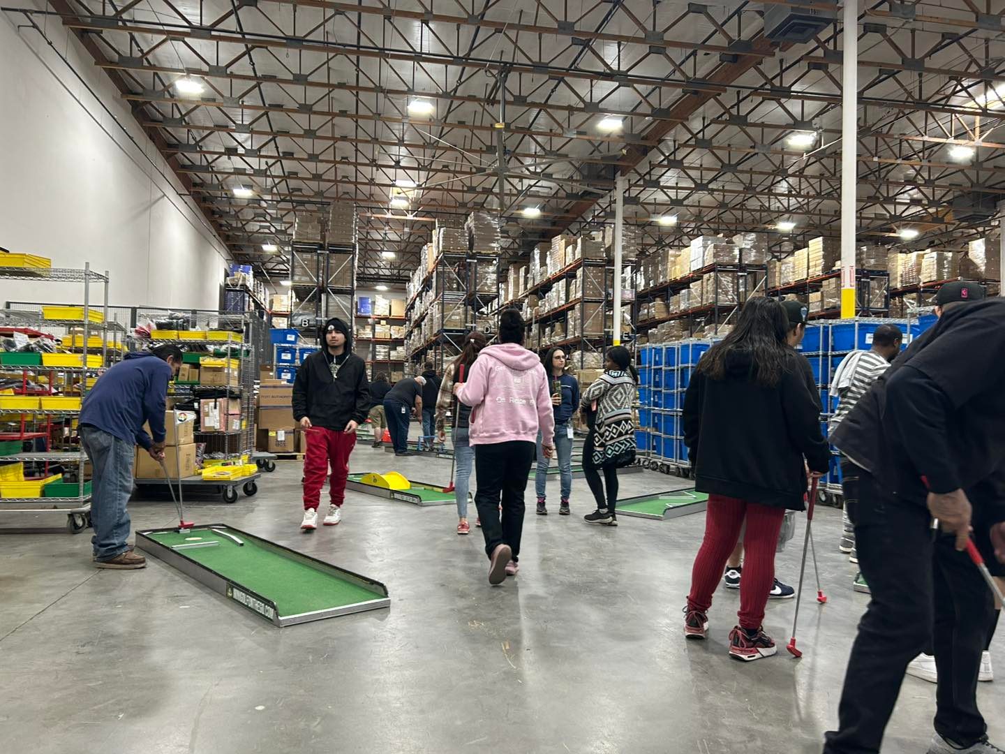 Employees playing mini golf set up inside a warehouse during a daytime company event