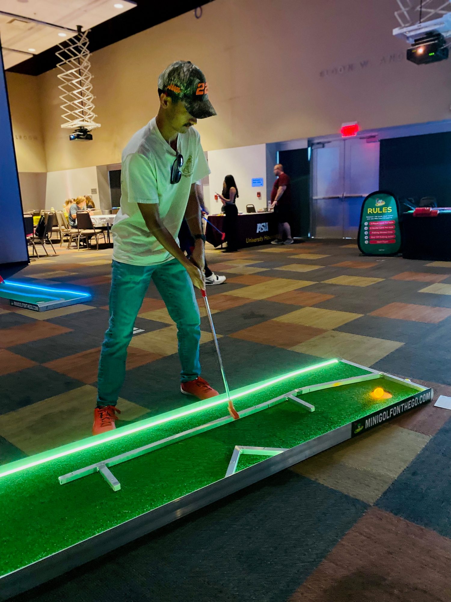 Guest putting on a glowing mini golf hole in a ballroom