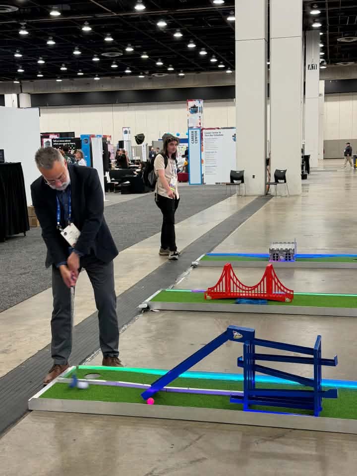 Convention attendee putting on a portable mini golf course in a convention center expo hall