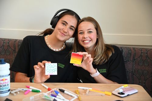 Two students holding their paintings and smiling