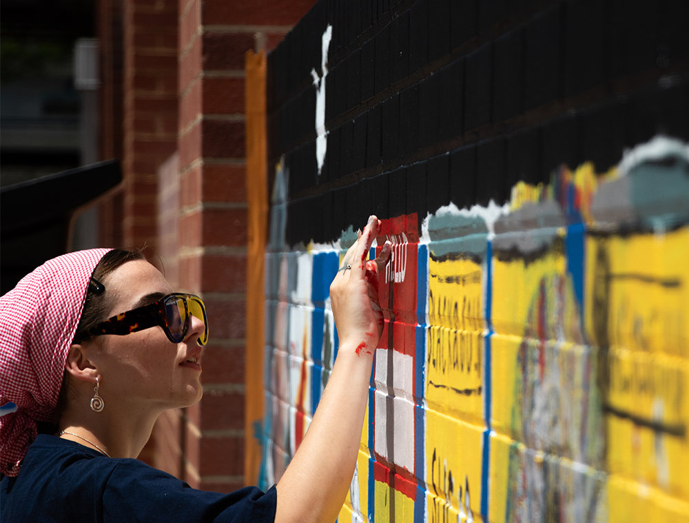 Student painting a mural on a wall