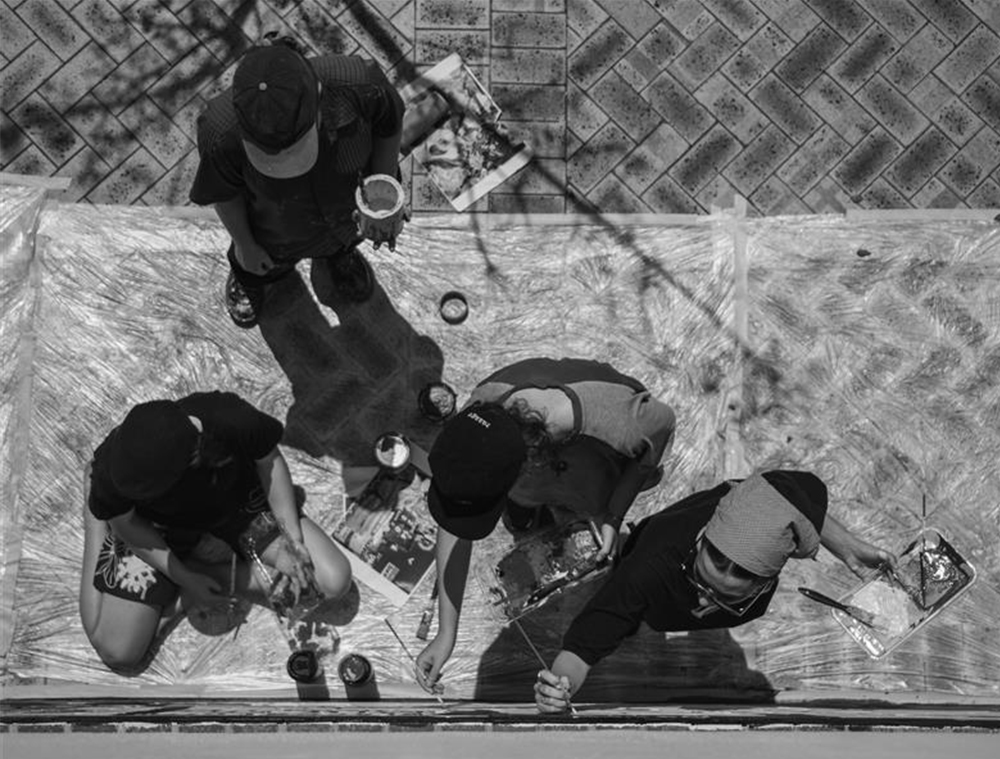 Black and white bird's-eye view of students painting a mural