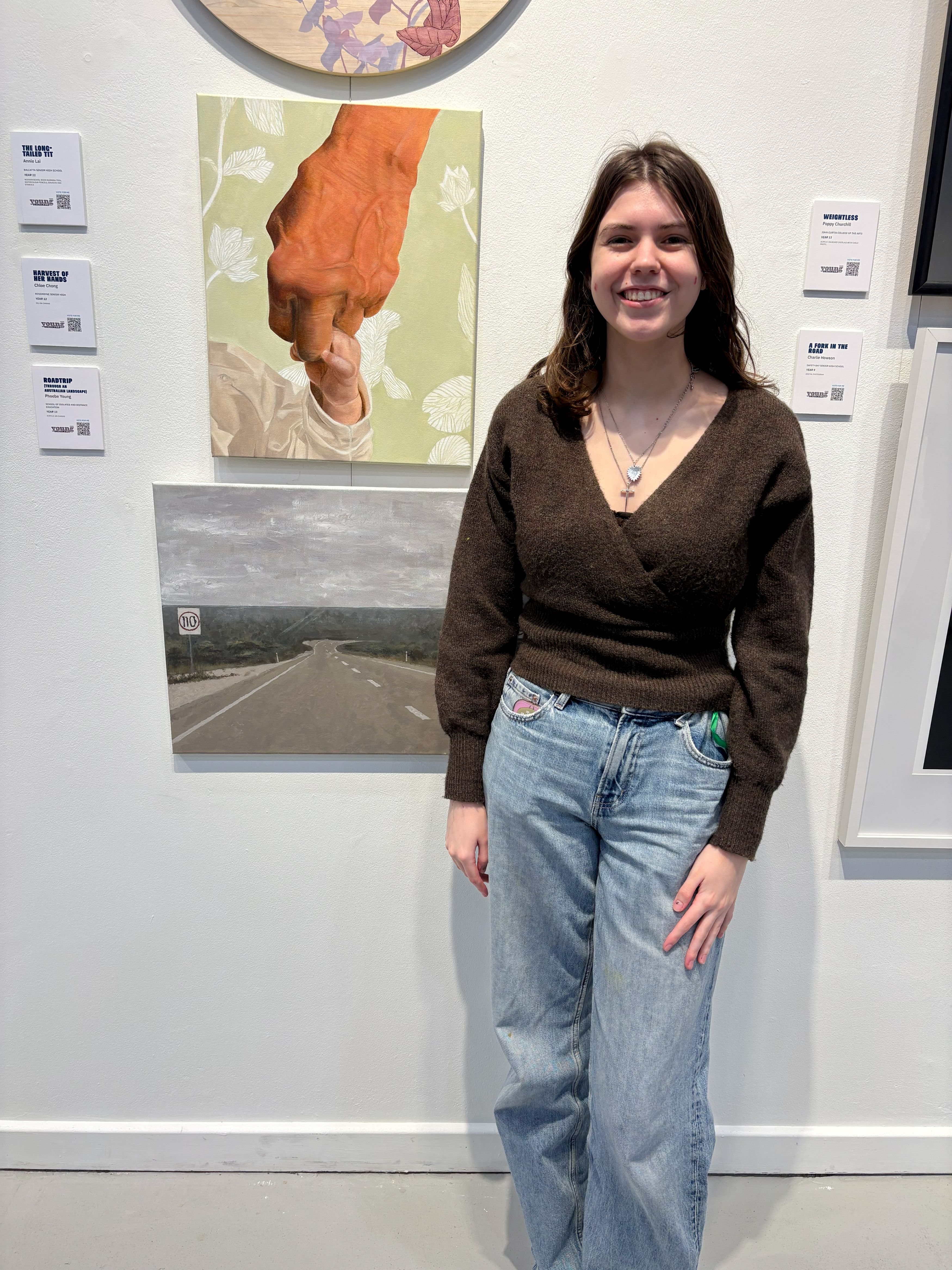 Young female stood by her artwork at an art exhibition