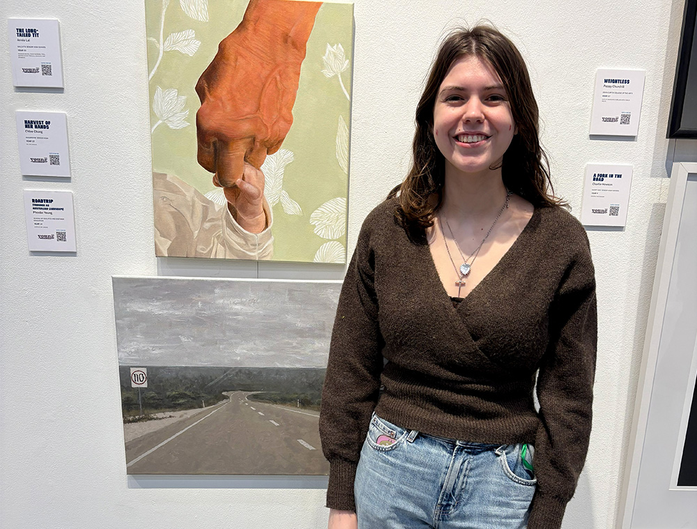 Young female stood by her artwork at an art exhibition