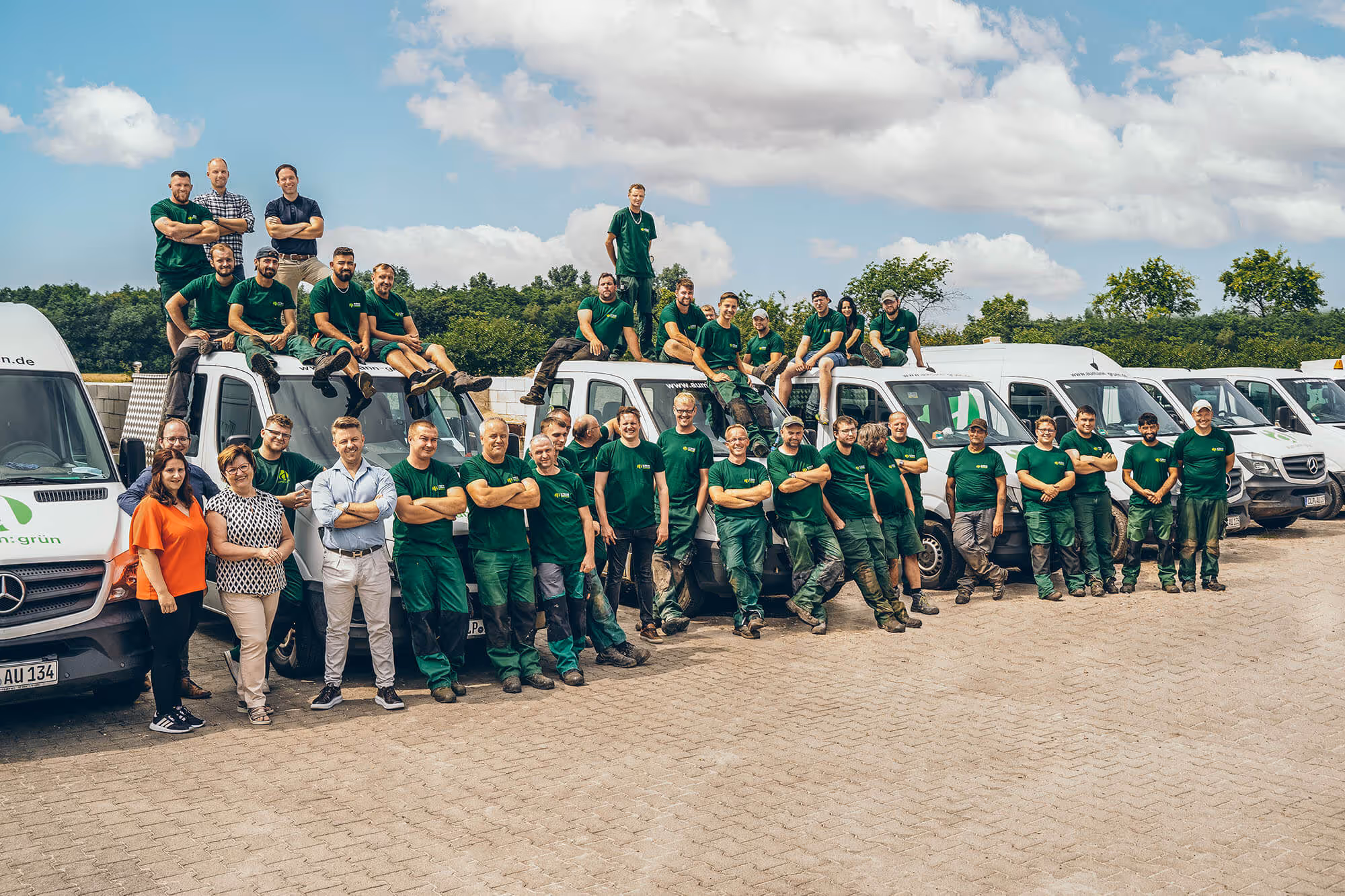 Die Mitarbeiter von Aumann Grün versammeln sich vor ihrer Autoflotte.