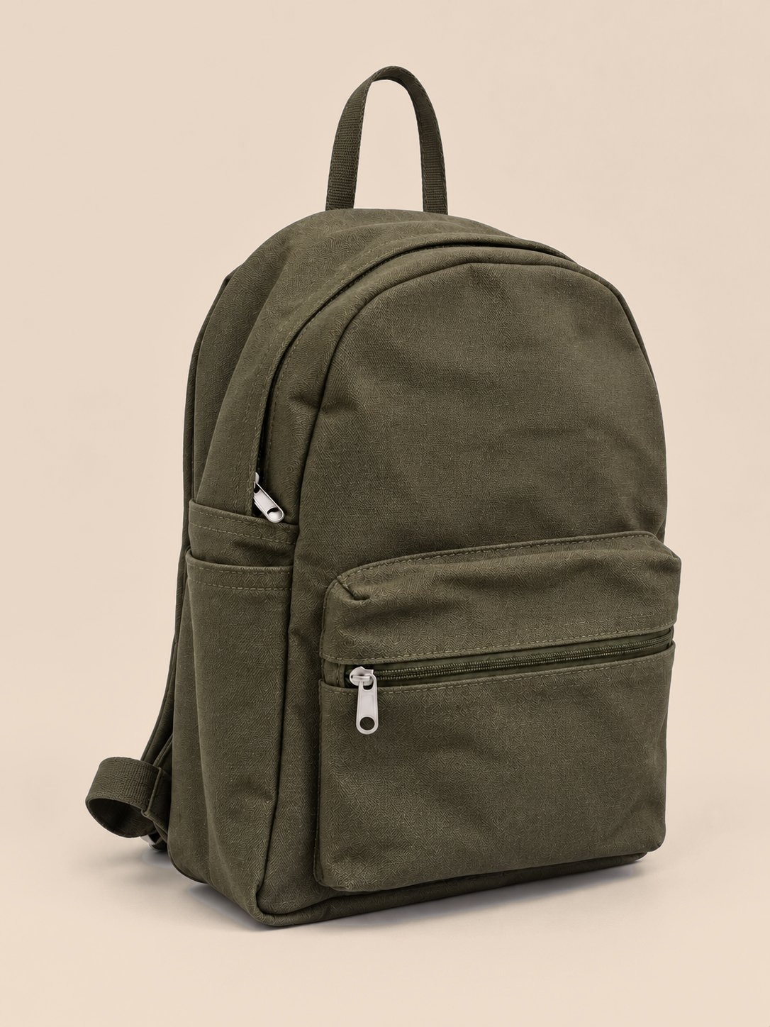 A deep olive green that goes with everything. This backpack is made from solid olive cotton canvas, coloured the same all the way through, with a matching olive lining.

It has a large zippered front pocket for your phone, passport and small items, open side pockets for a bottle or umbrella, and an interior organiser with a card slot and a loop for keys or sunglasses. A top carry handle and silver-tone zips finish it off.

Material: 100% cotton
Dimensions: 40 × 32 × 13 cm