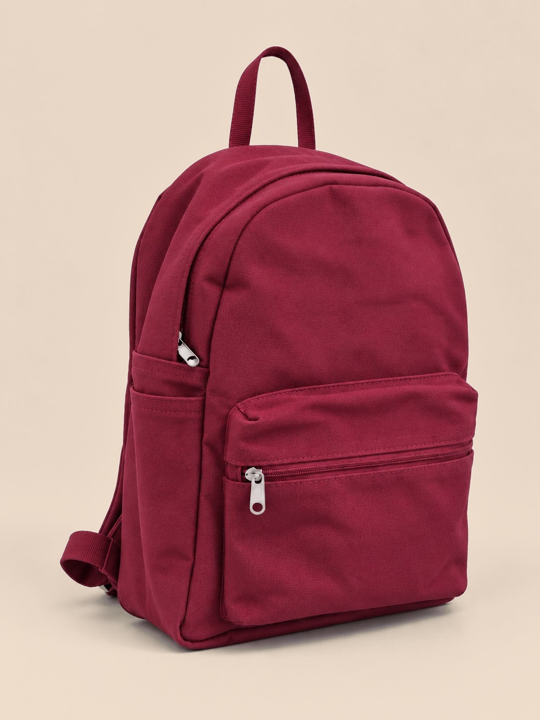 A rich, warm maroon with a hint of pink. This backpack is made from solid maroon cotton canvas, coloured the same all the way through, with a matching maroon lining.

It has a large zippered front pocket for your phone, passport and small items, open side pockets for a bottle or umbrella, and an interior organiser with a card slot and a loop for keys or sunglasses. A top carry handle and silver-tone zips finish it off.

Material: 100% cotton
Dimensions: 40 × 32 × 13 cm