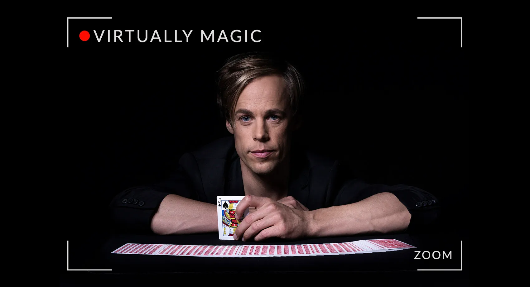 Jacob Schenström sitter vid ett bord med en kortlek utspridd. Digital magi via zoom.