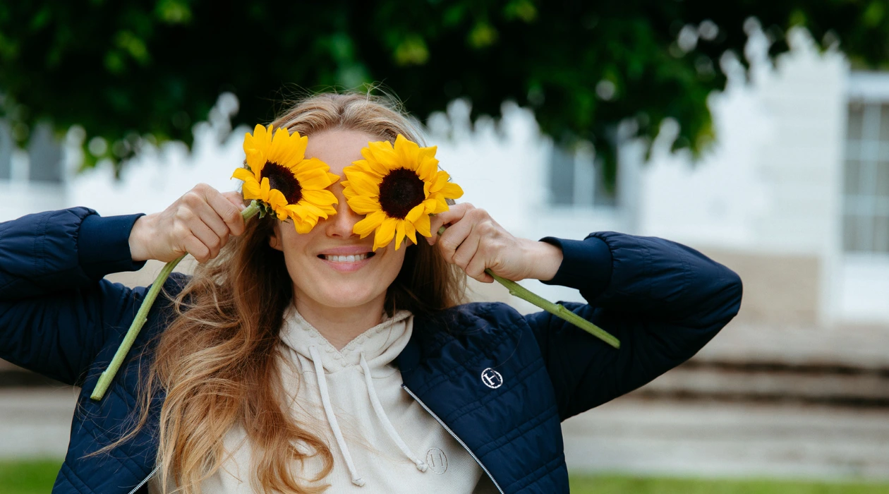 A woman smiles while holding flowers in her hands.