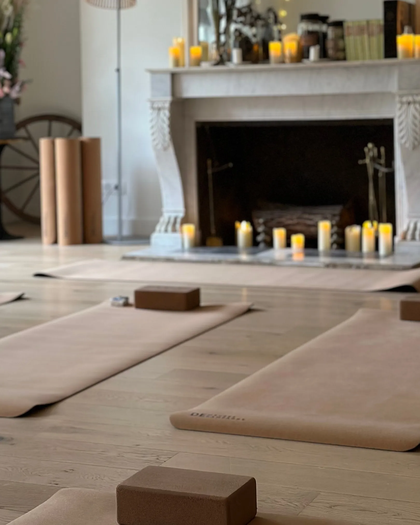 Des tapis de yoga sont placés dans une belle salle, illuminée par des bougies