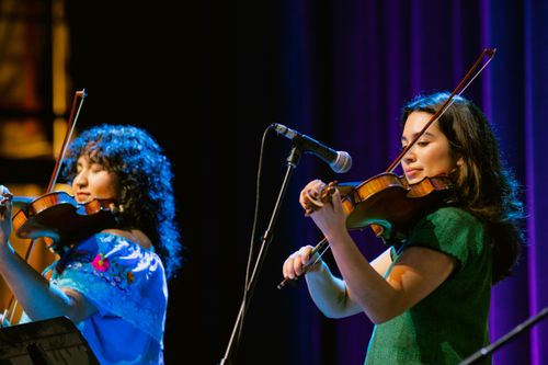 A close-up image of two young women playing violin.