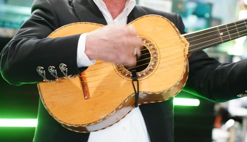 A close-up photo of a vihuela held against a person’s torso.