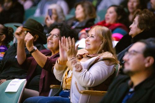 An audience smiles and applauds.