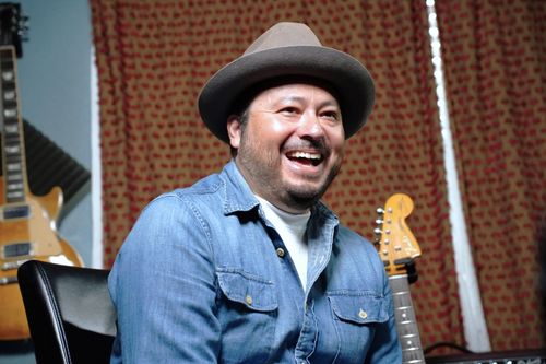 Carlos Rodríguez, a man in a light blue, button-down shirt, smiles broadly.