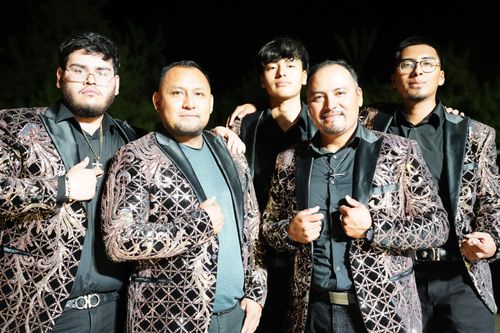 A band of five musicians in matching suits pose for a group picture. Gerardo Ramírez is in the front on the right.