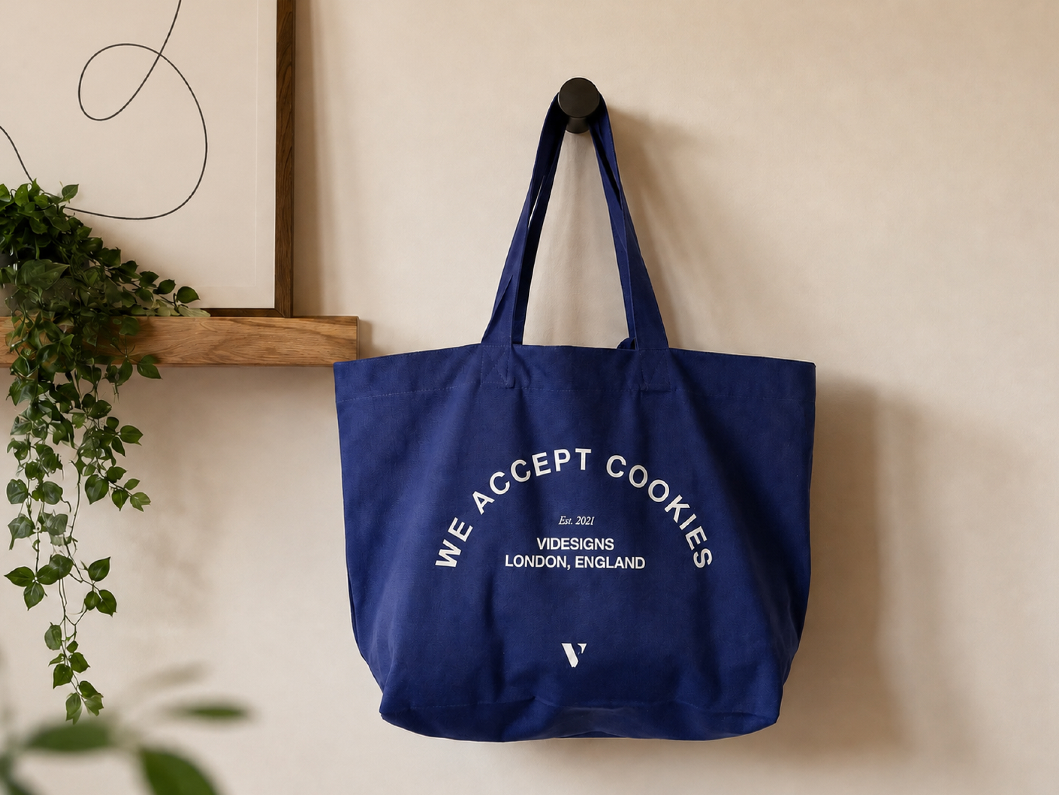 Blue tote bag hanging on a hook with text saying We Accept Cookies, Videsigns, London, England.