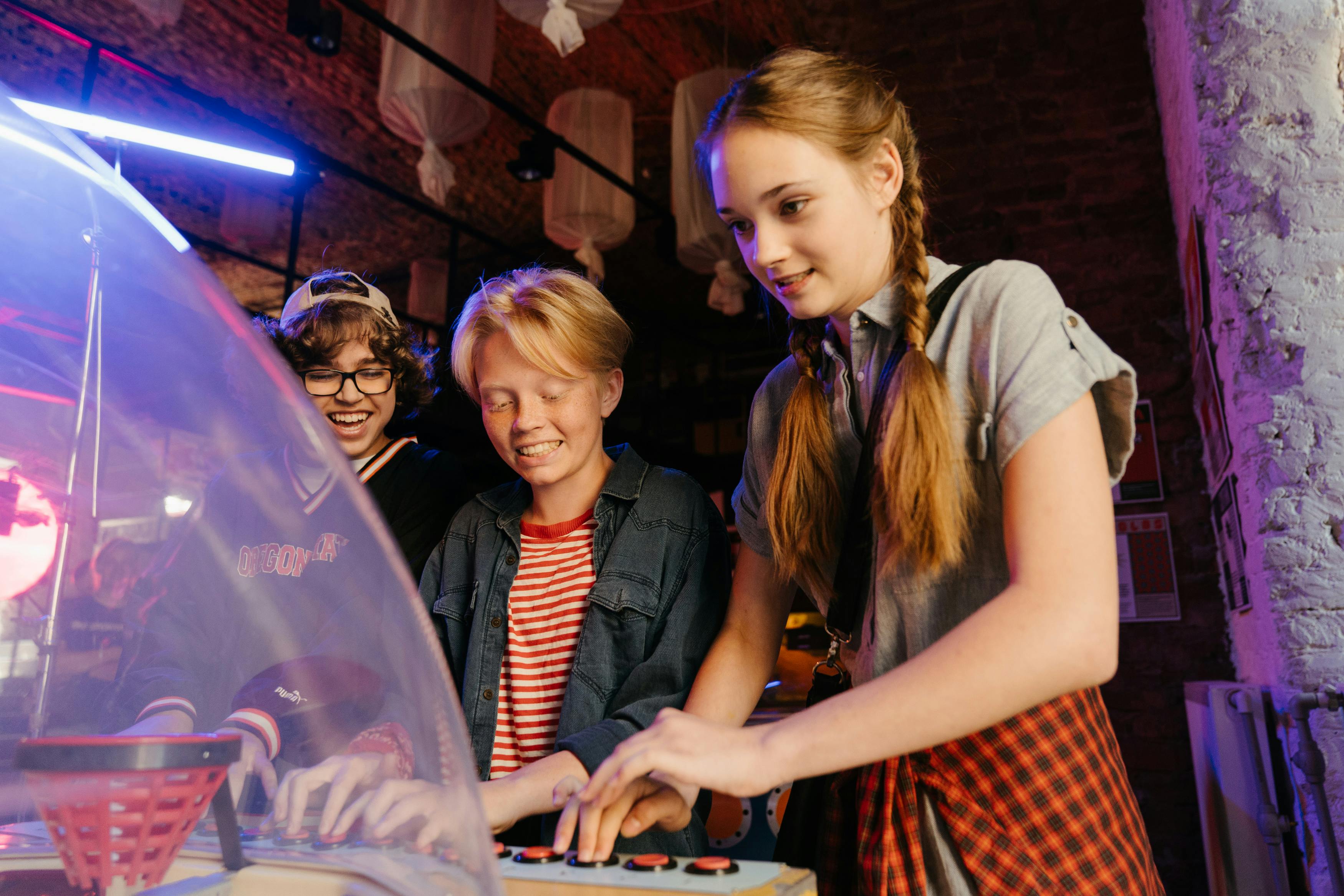 three teens playing an arcade game