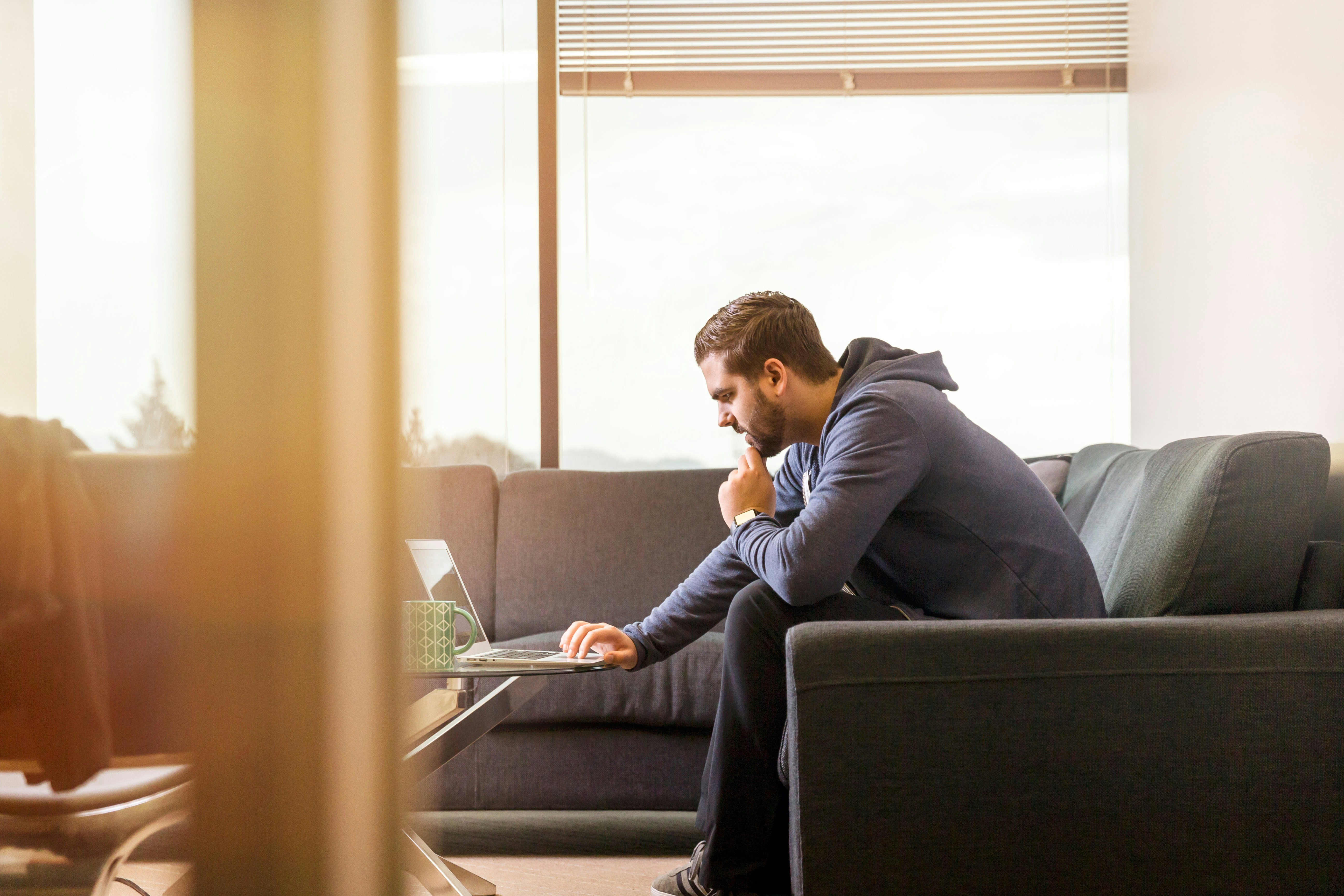 man sitting on a sofa and working on a latop - How To Use Webflow Templates