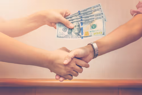 Money being exchanged with a handshake