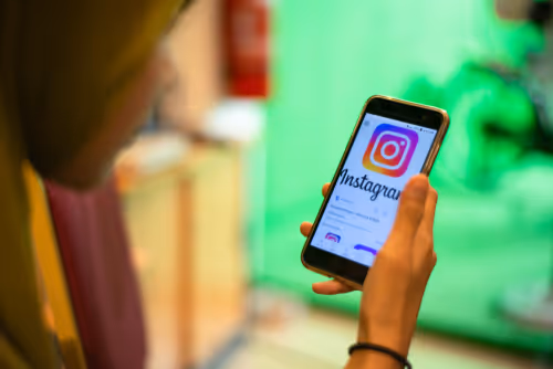 girl holding phone and on screen it shows Instagram