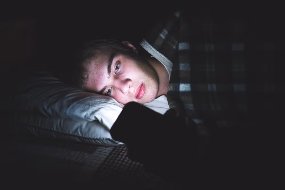 Boy using phone in bed