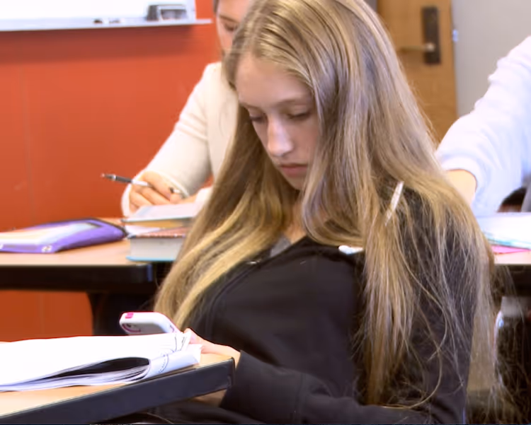 Teen girl on phone in class