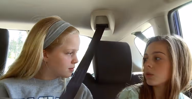 2 girls in a car looking at each other 