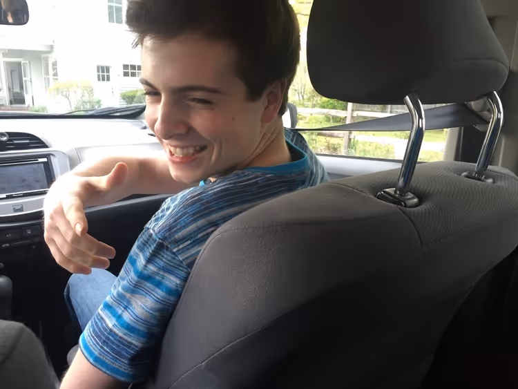 Man smiling in car holding his hand out