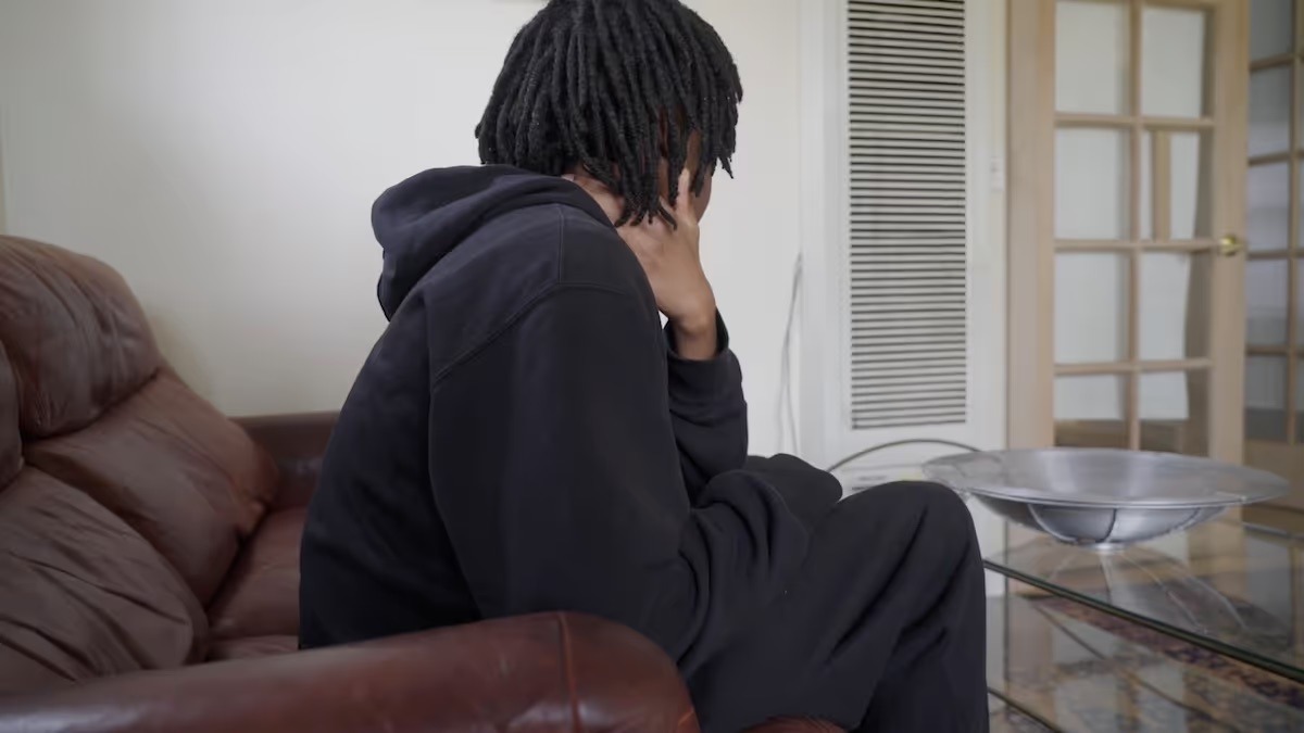 Teen boy sat on chair facing away from camera.
