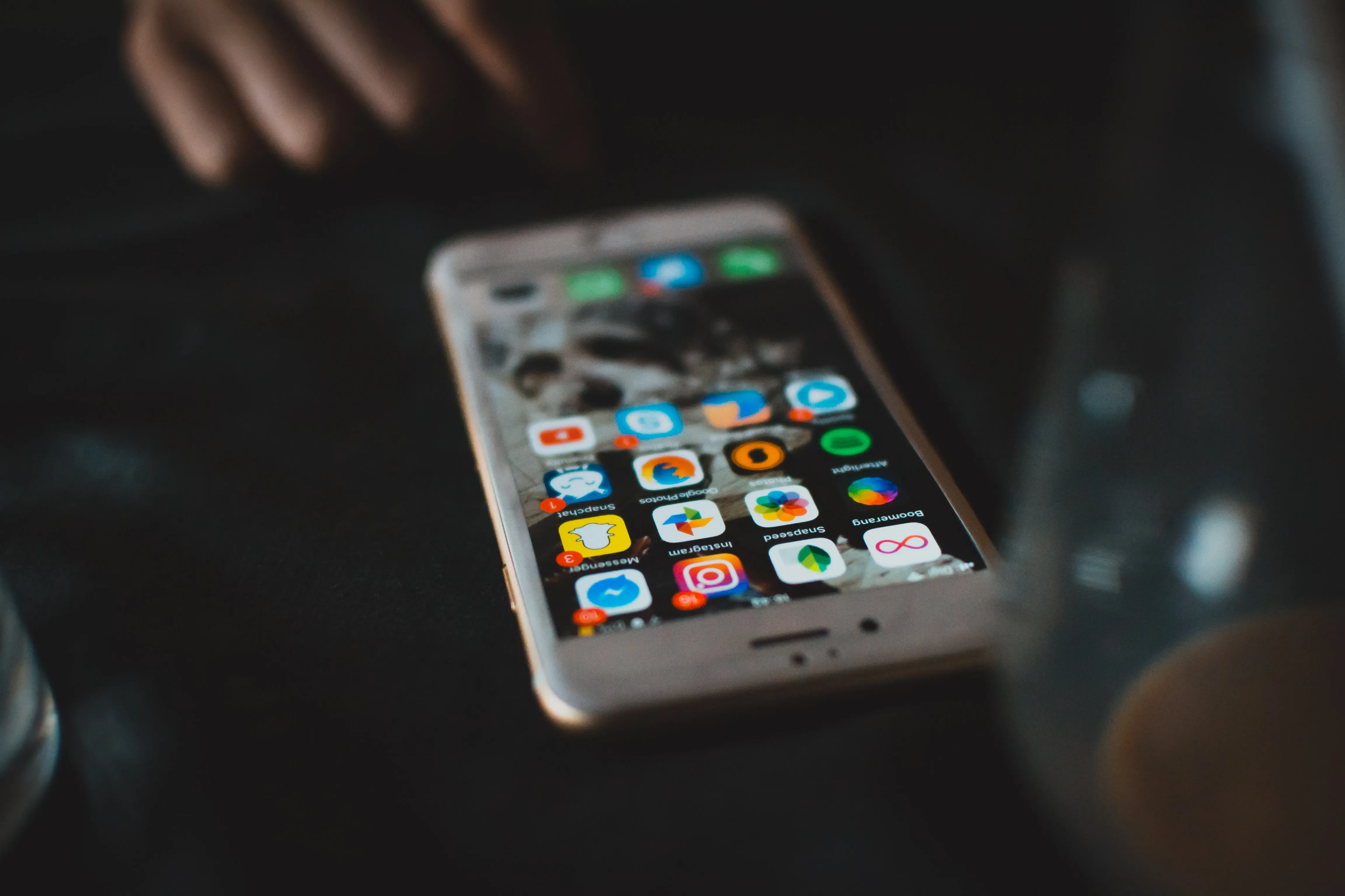 Cellphone on a black table showing someone's apps on their screen