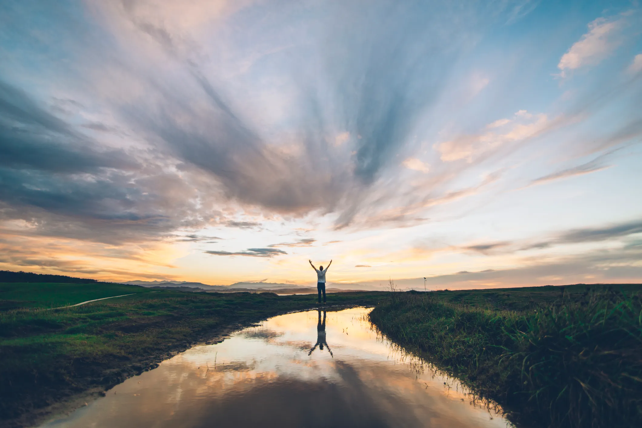 Person with their arms up embracing the sunset in the water