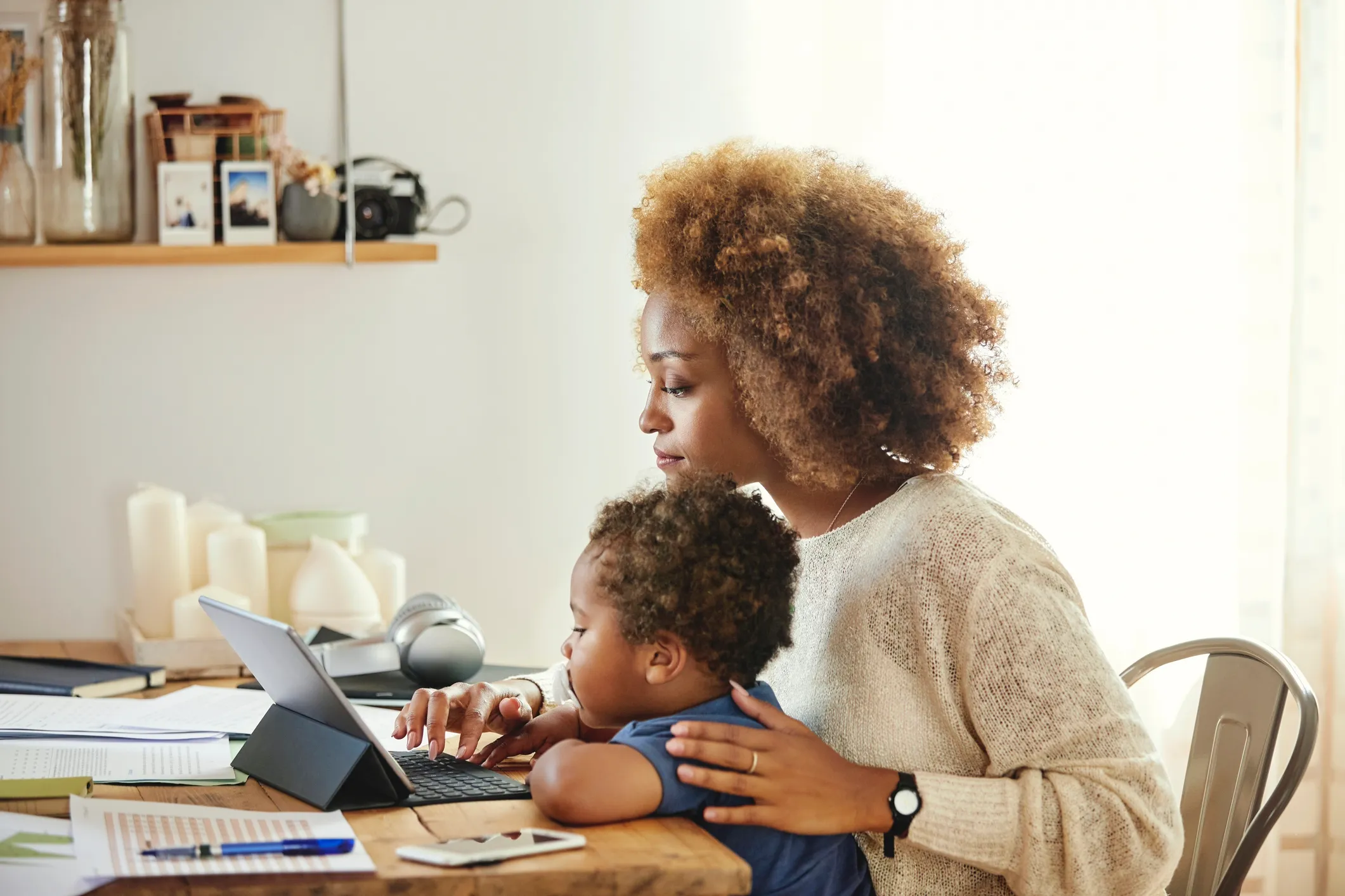 Single mother holding her child while working on a laptop