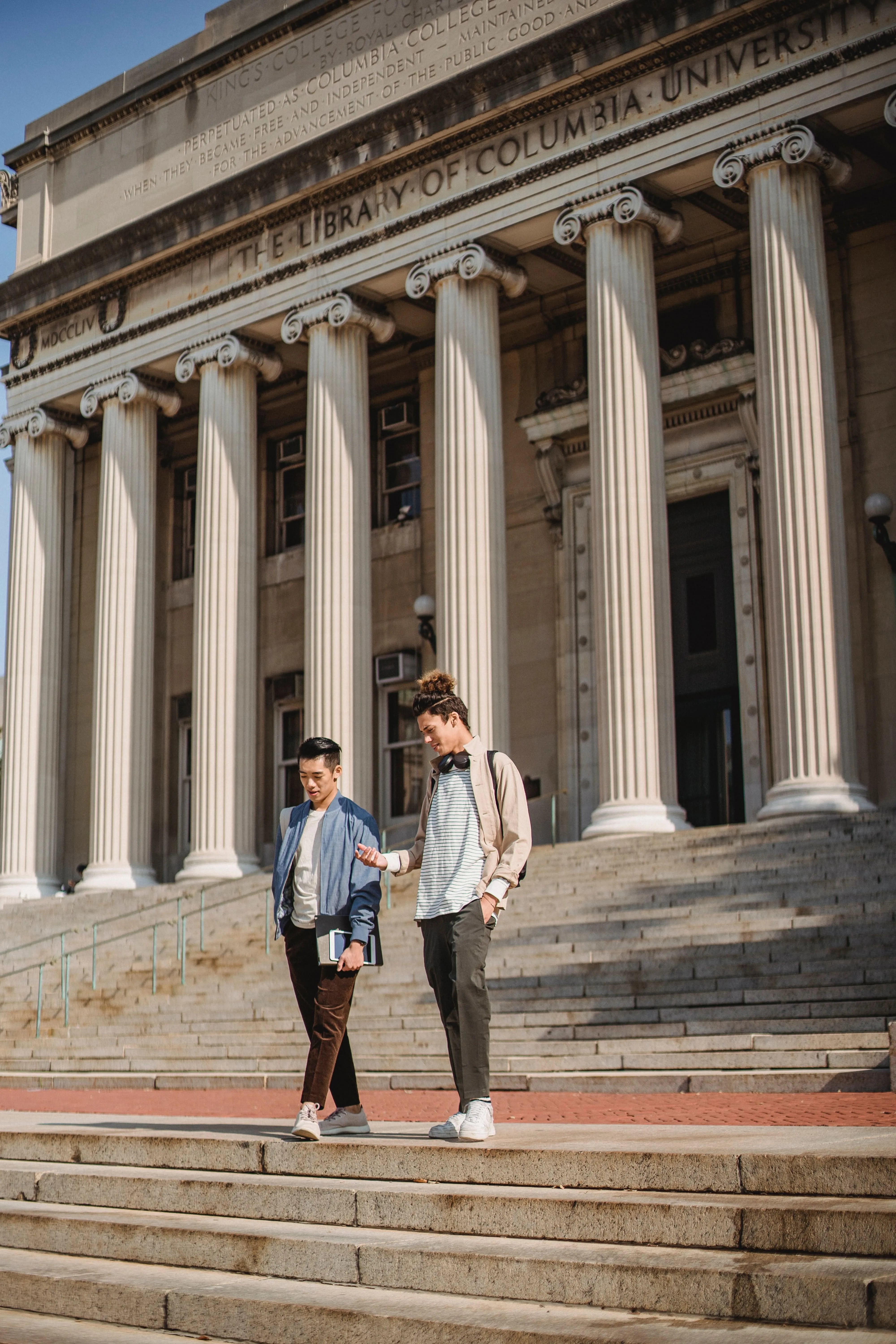 Two college students walking down a flight of stairs