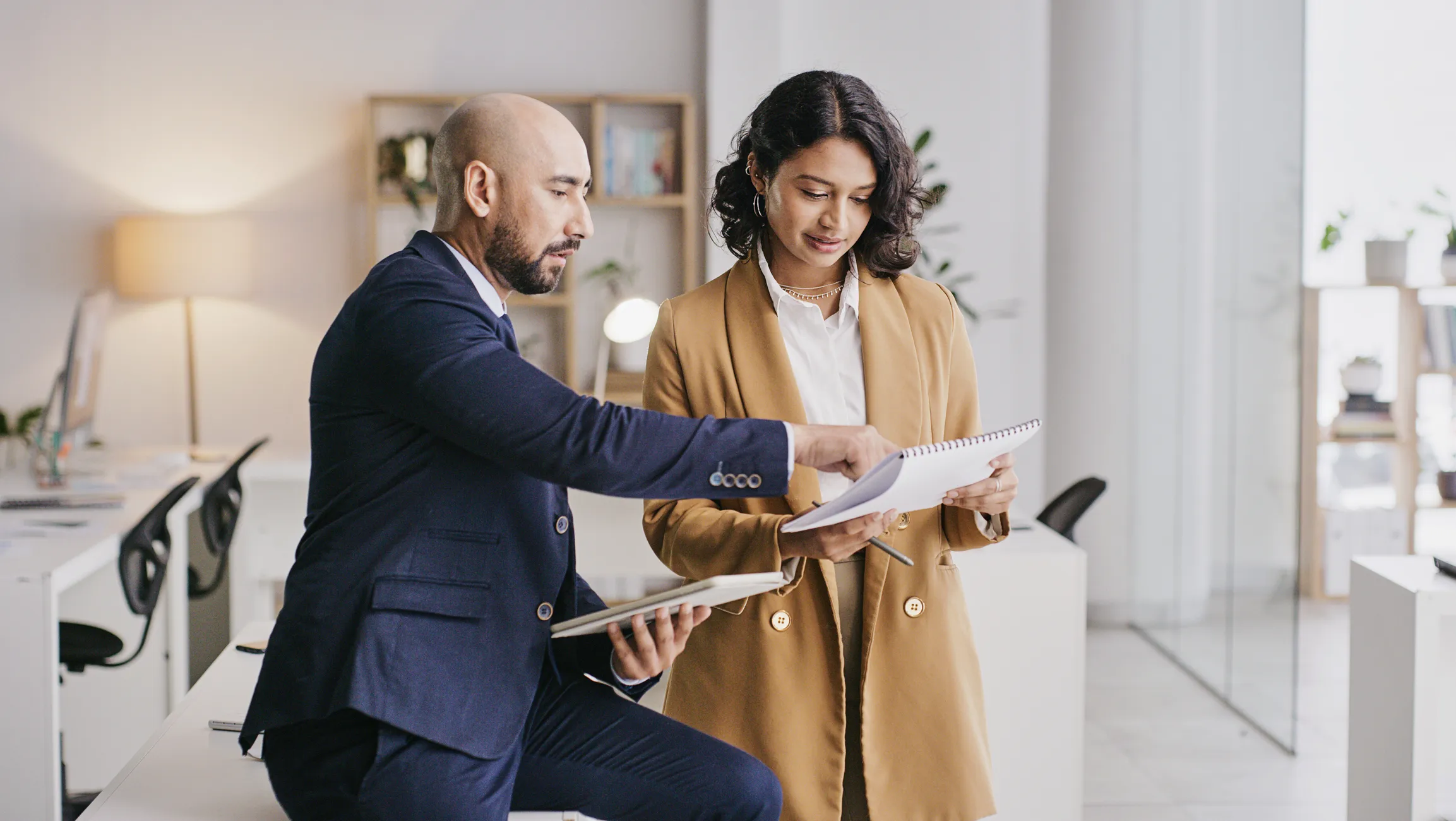 Woman and man standing side by side, man pointing to paper woman is holding