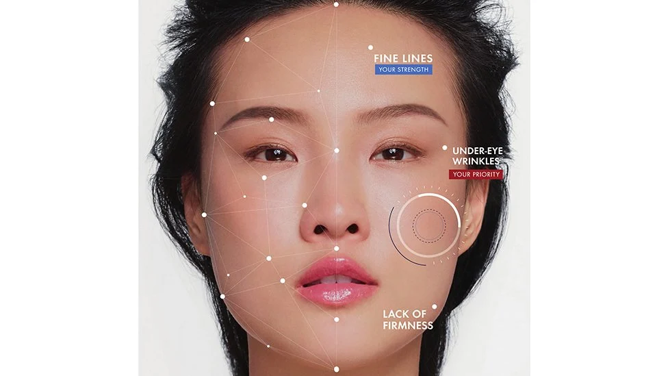 A woman faces the camera. Overlaid on her image are graphic points with lines between them, and three dots analyzing facial features: “Fine Lines, Your Strength,” “Under-Eye Wrinkles, Your Priority,” and “Lack of Firmness.”