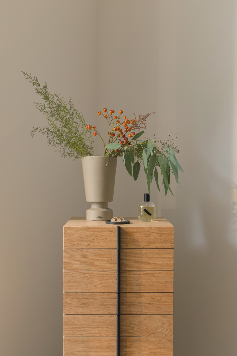 Schmuck neben einer Vase mit Blumen auf einem japanischen Holzmöbel