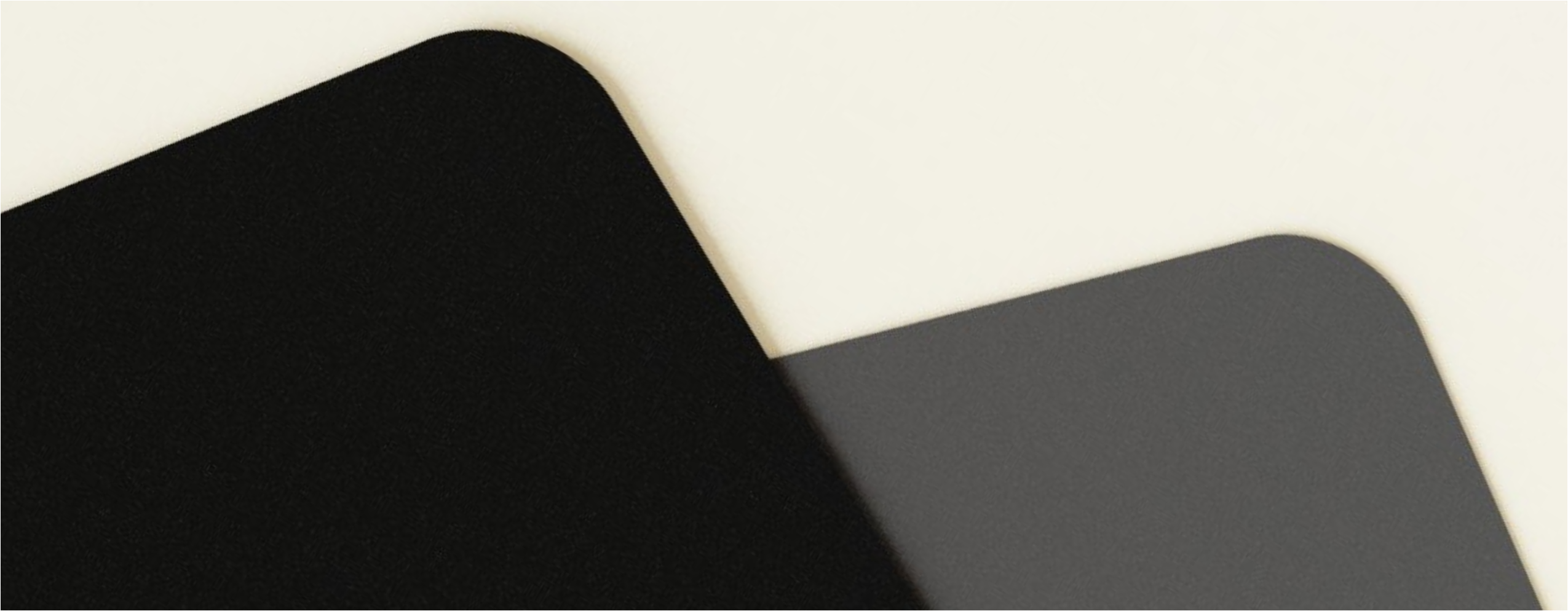 Microrubber base of a PAVED™ mousepad with rounded corners, one black and one dark gray.