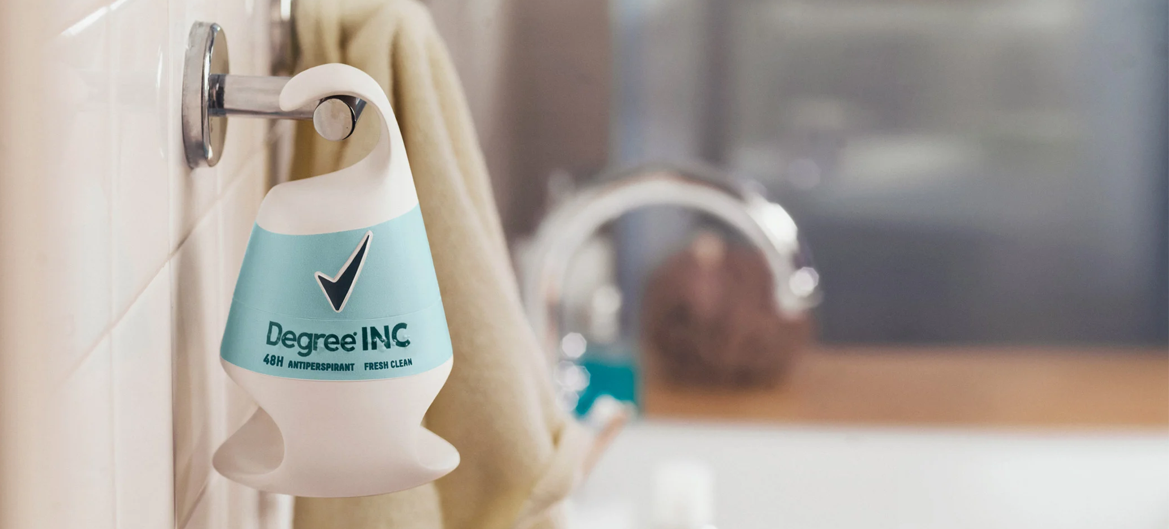 Close-up of the Degree Inclusive adaptive deodorant hanging on a bathroom hook, showcasing its unique ergonomic shape designed for one-handed usage.