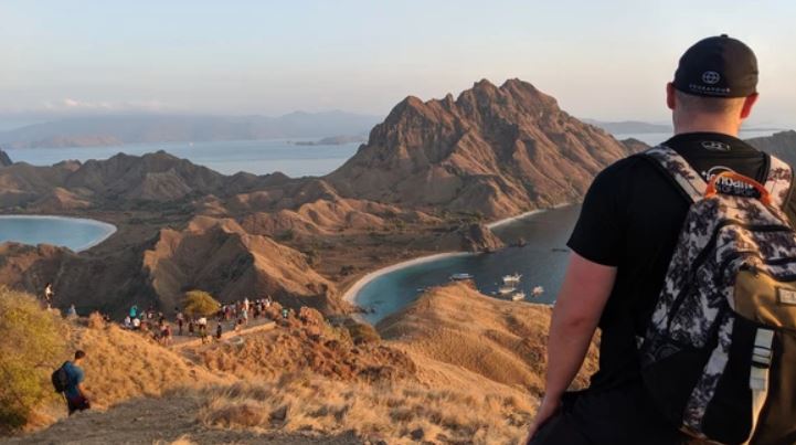 Man overlooking scenic coastline with backpack – financial freedom and retirement lifestyle Canada