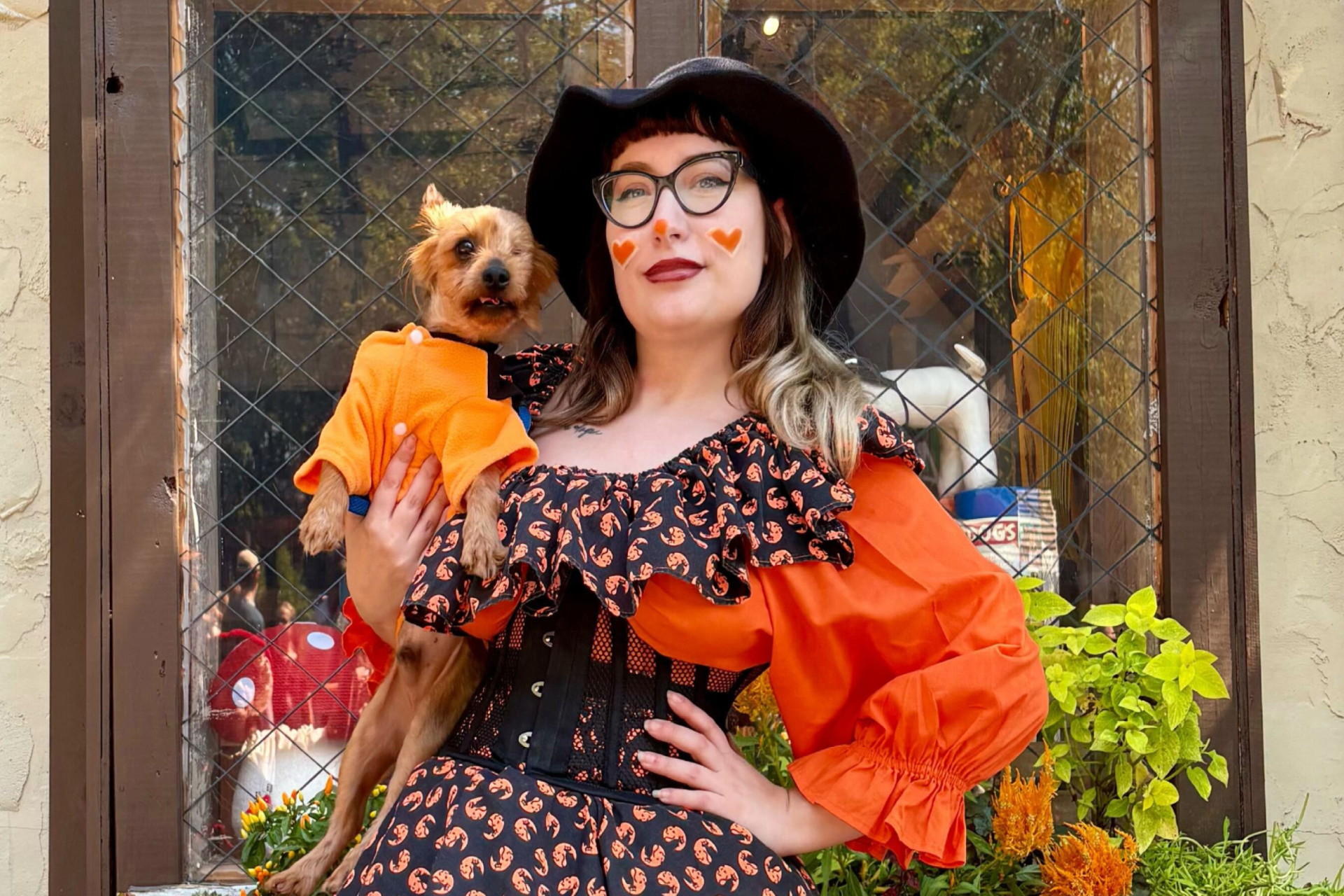 A woman dressed up for Halloween with a small dog in costume
