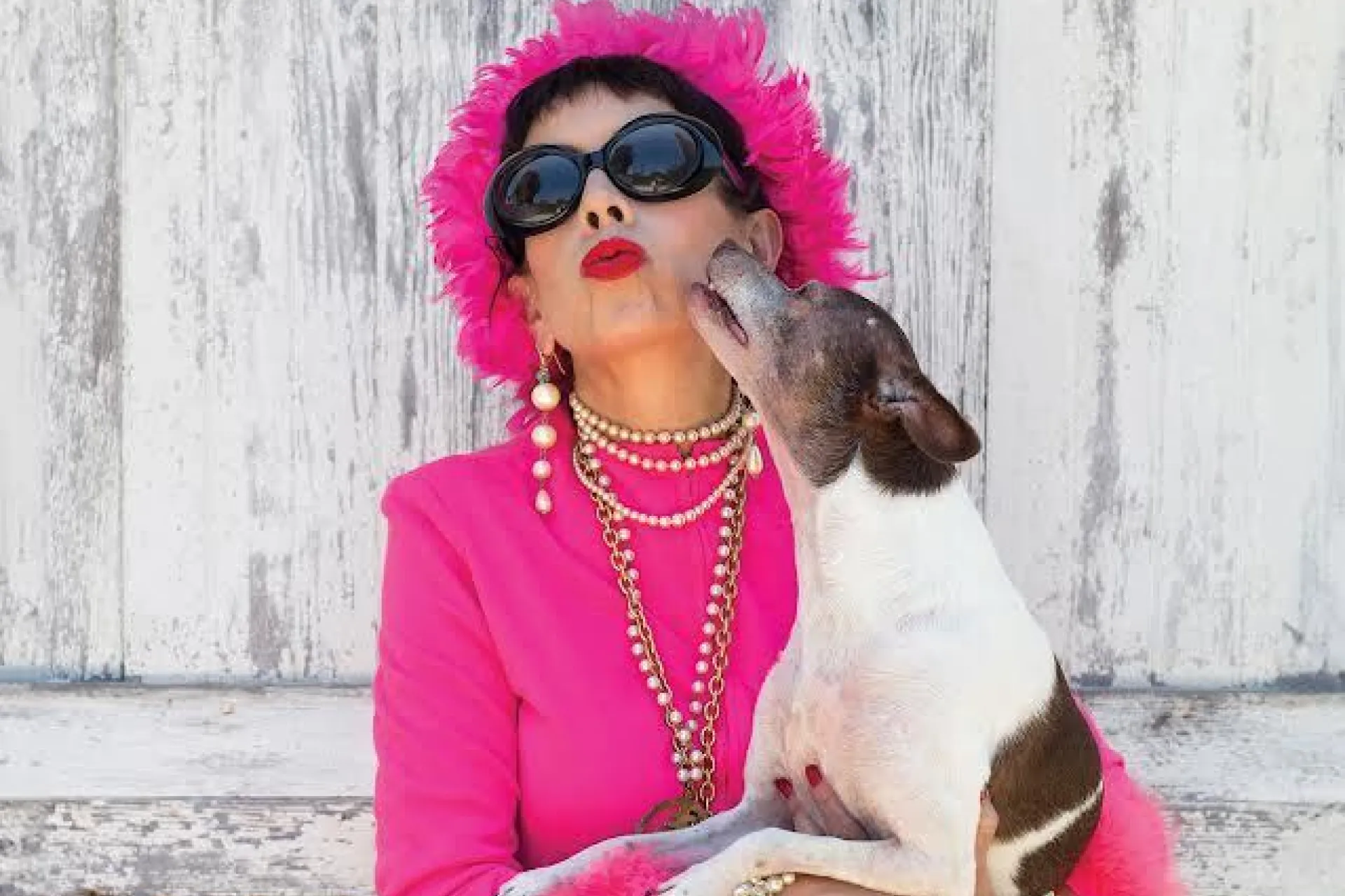 Dog kissing a woman in a pink outfit