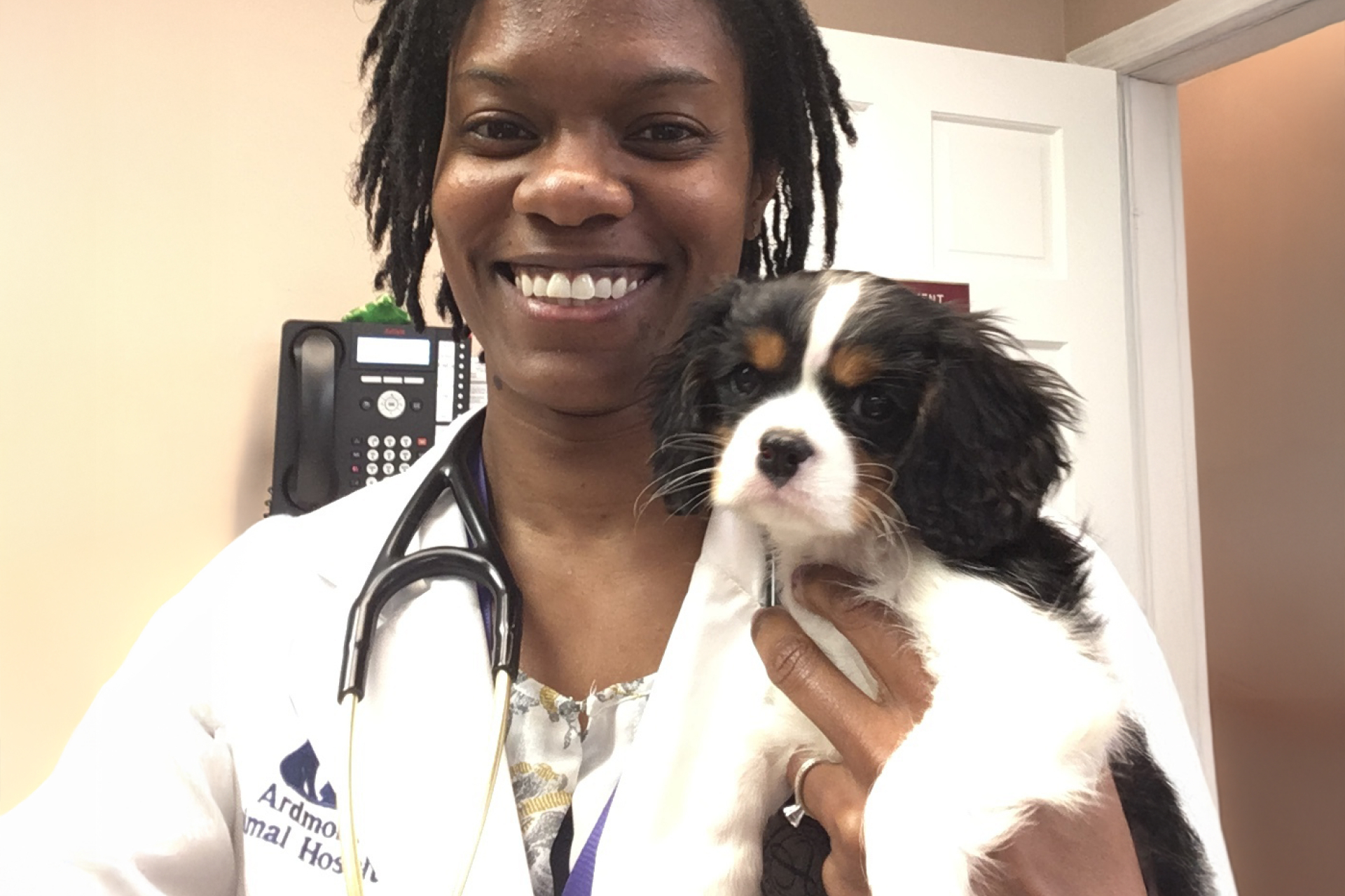 Veterinarian Dr. Aliya McCullough wearing a stethoscope and holding a Cavalier King Charles