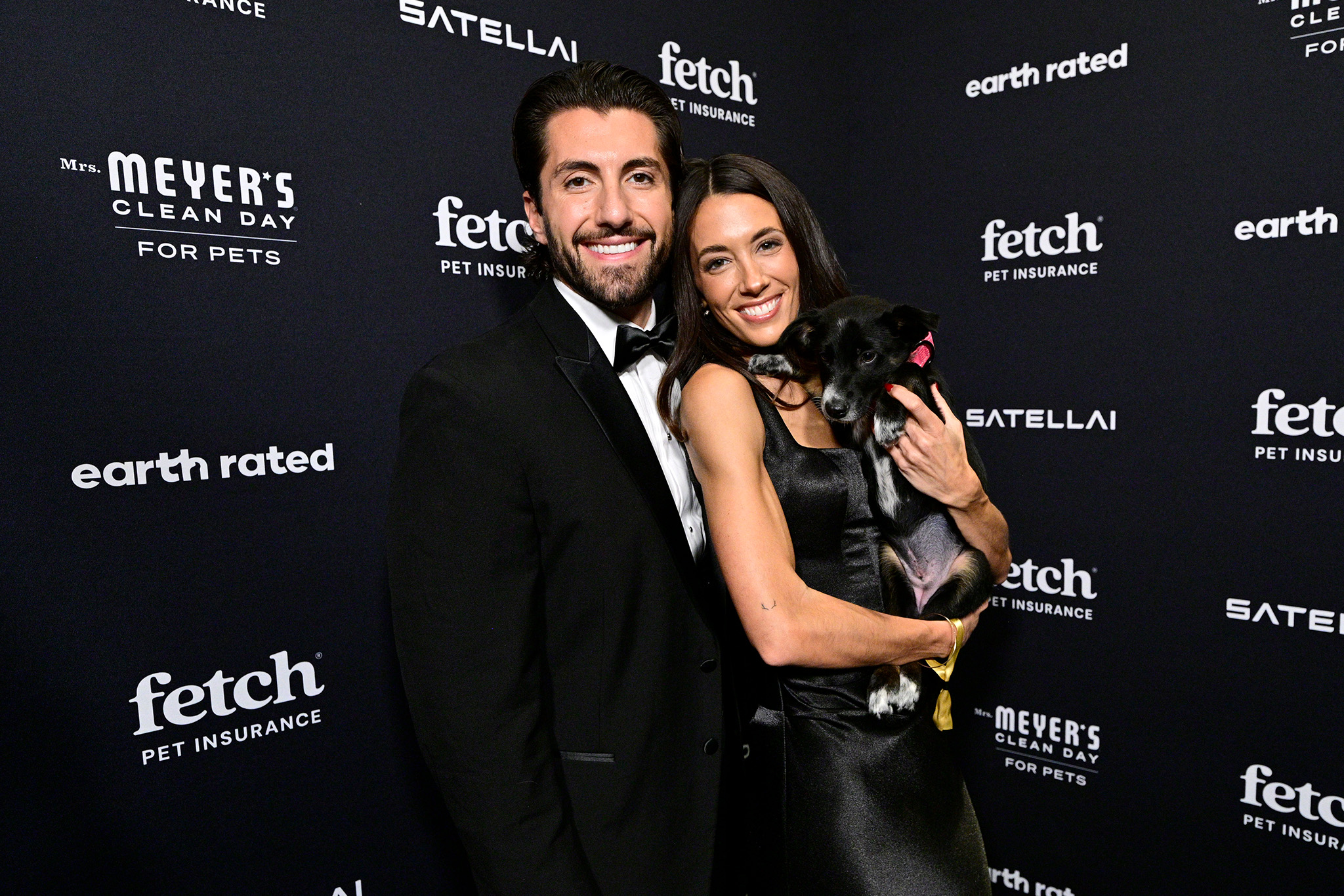Kathryn Hurley and Jason Tartick pose on the green carpet with a pup from North Shore Animal League wearing a SATELLAI Go Collar at the 2026 Fetch Pet Gala.