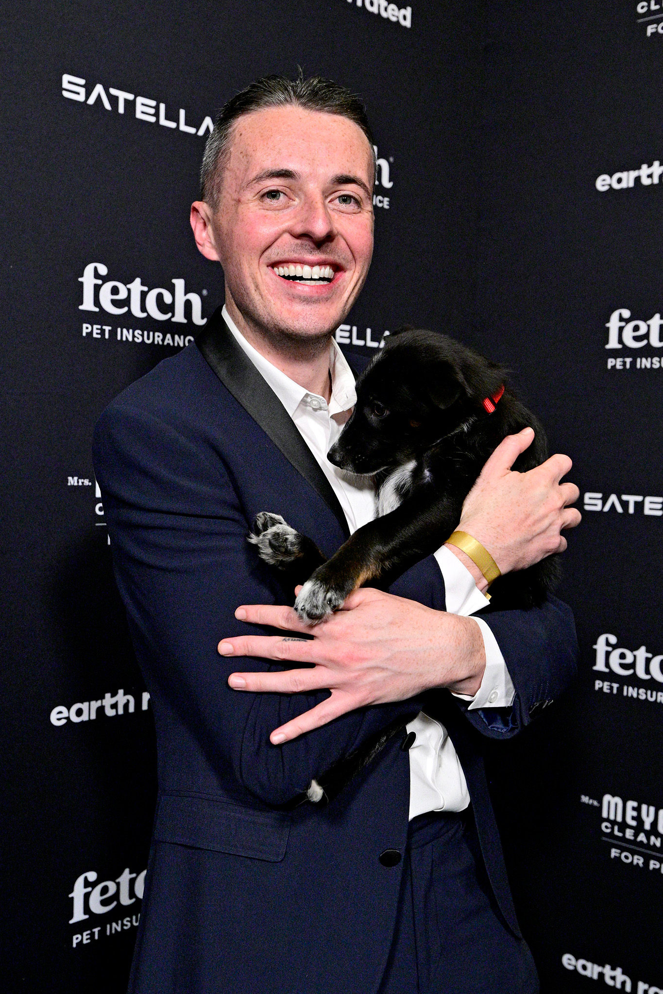 Guest poses on the green carpet with a pup from North Shore Animal League wearing a SATELLAI Go Collar at the 2026 Fetch Pet Gala.