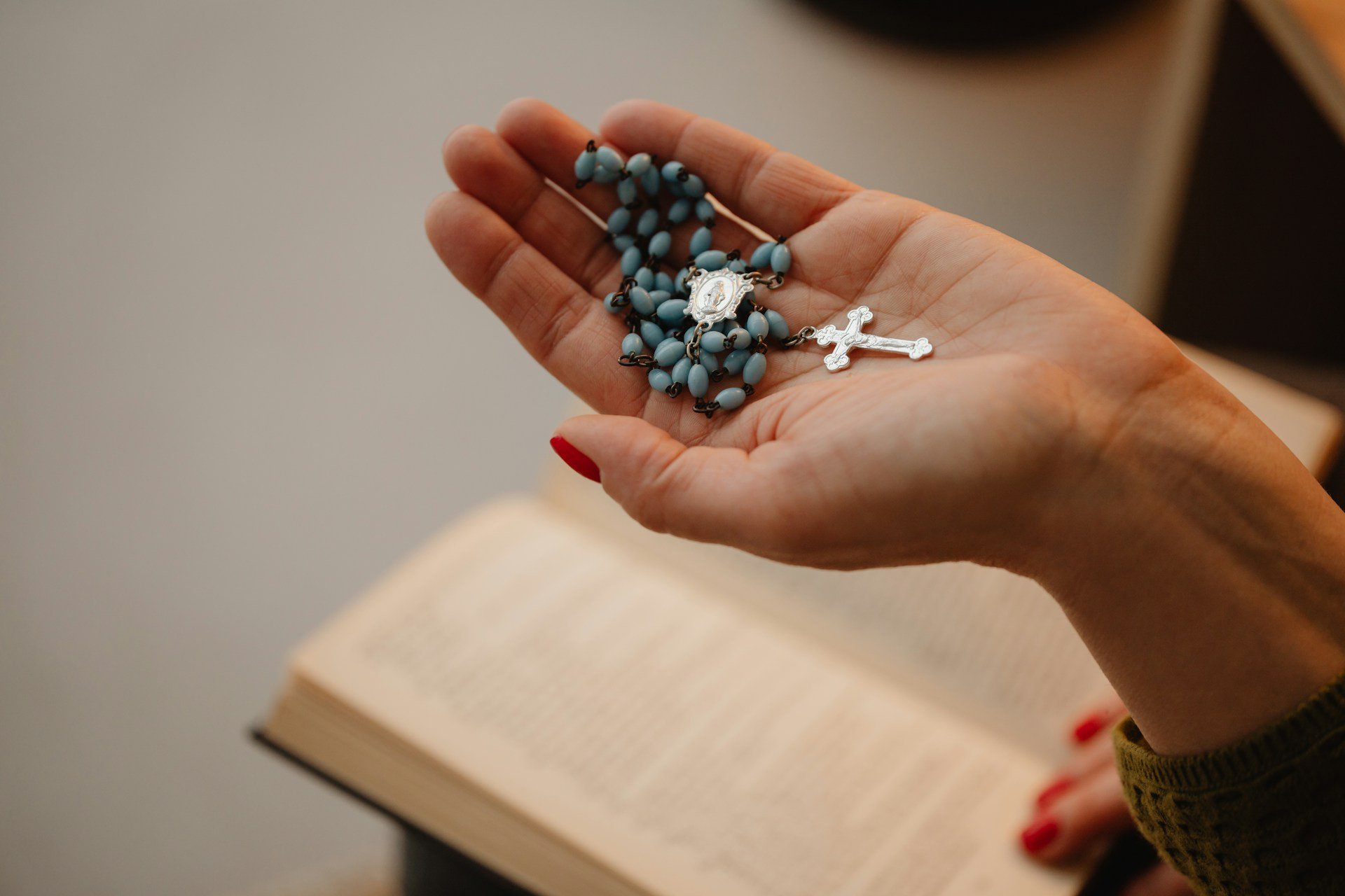 Rosary beads held in an open hand over a book